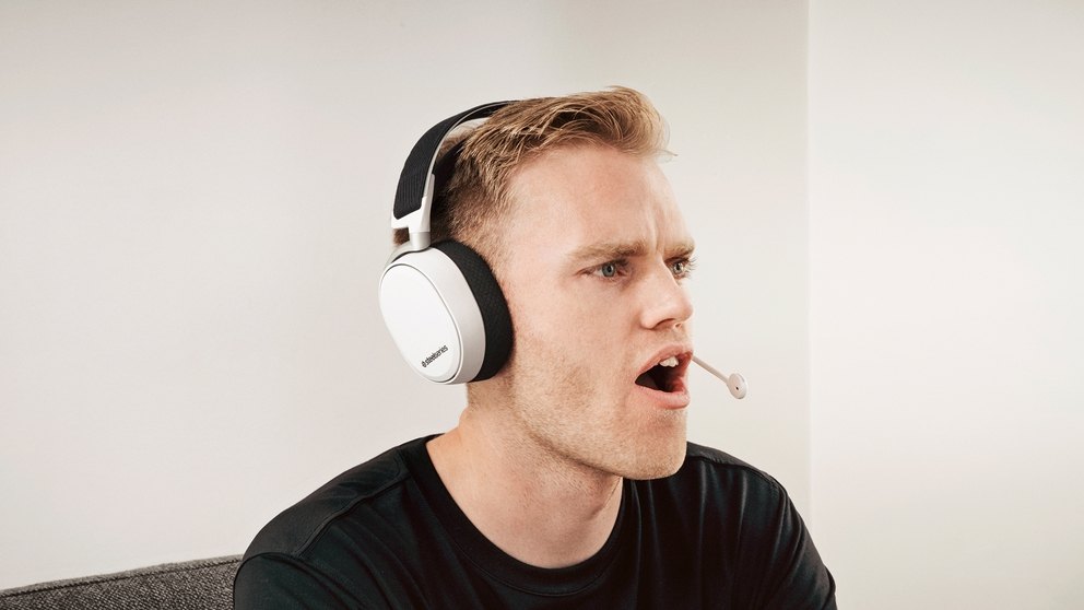 
 A user smiling while wearing the Arctis Pro Wireless White, microphone in the extended position.
 